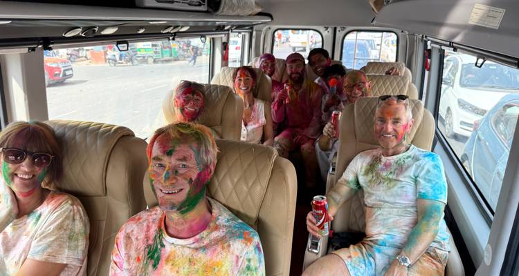 Groupe de personnes souriantes à l'intérieur d'un véhicule après la célébration de Holi.