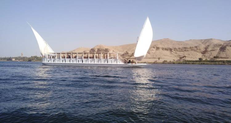 Sailing vessel on a river with desert landscape.