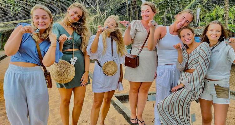 Groupe de femmes posant sur une zone sablonneuse.