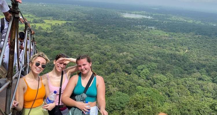 Trois femmes posant sur un point de vue élevé avec une vue immense en arrière-plan.