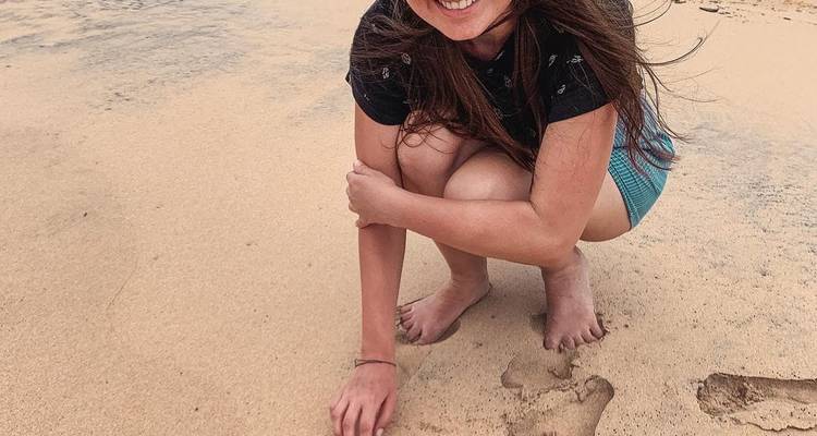 Woman crouching on the sand at the beach.