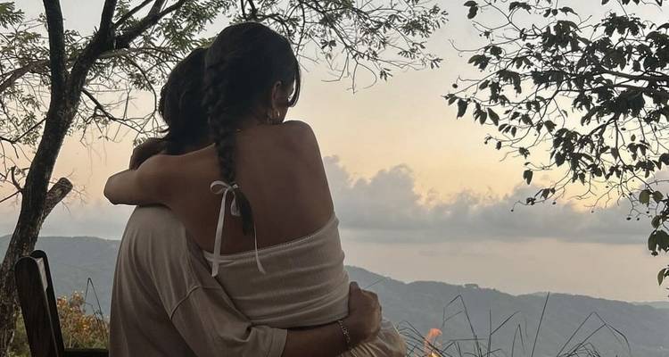 Couple embracing on a mountain viewpoint at sunset.
