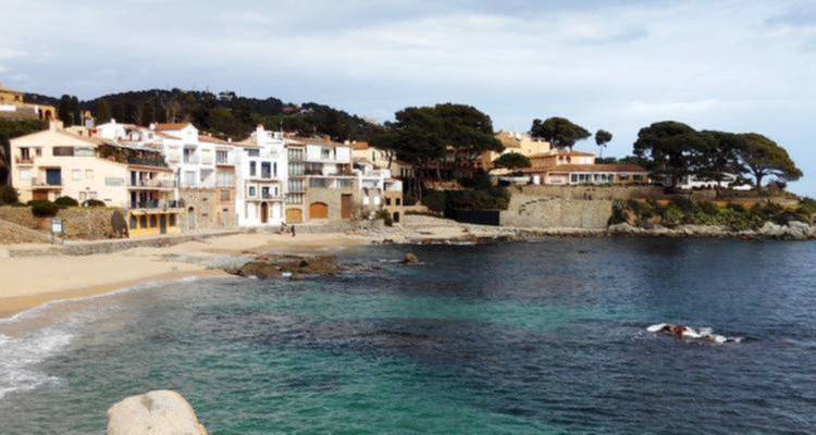 Pueblo costero con playa y edificios junto al mar.