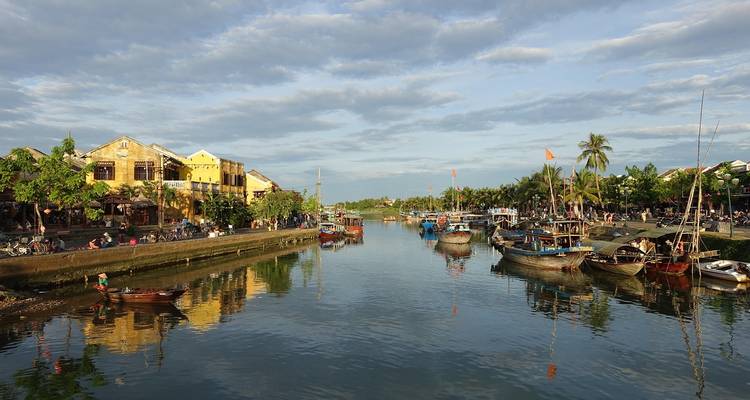 A lively riverside town with various boats and people.