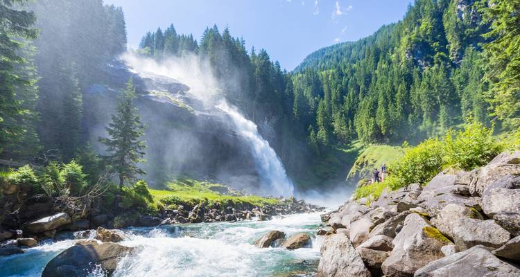 Ein dramatischer Wasserfall, der in einer üppigen Waldlandschaft herabstürzt.