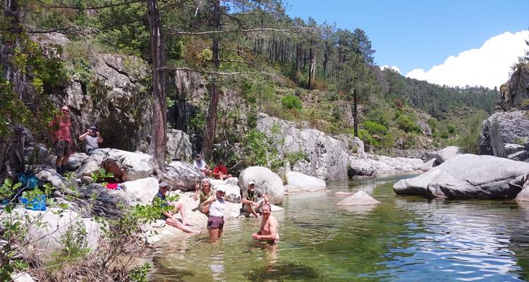 Wanderer kühlen sich in einem klaren Waldgestein-Felsenpool ab, der von Granitblöcken und Kiefern umgeben ist.