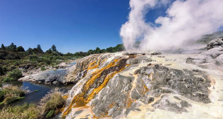 Zone géothermale fumante avec des formations rocheuses colorées.