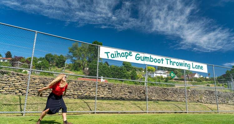 A young woman participating in a gumboot throwing competition.