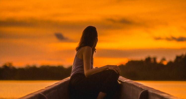 Une personne assise dans un bateau pendant un coucher de soleil éclatant.