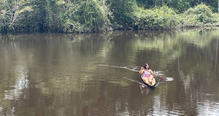 Een persoon die paddelt in een kano op een rivier.