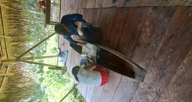Deux personnes travaillant à sculpter un canoë devant une hutte.