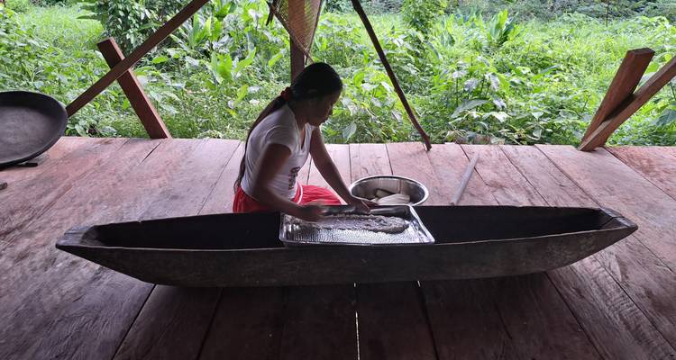Une personne travaillant à la préparation de nourriture dans un canoë.