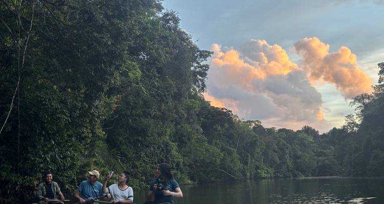 Un groupe de personnes sur un bateau sur une rivière au coucher du soleil.
