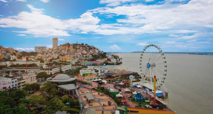 Vista aérea del malecón de Guayaquil con casas de colores en las laderas, una rueda de la fortuna y un amplio paseo.