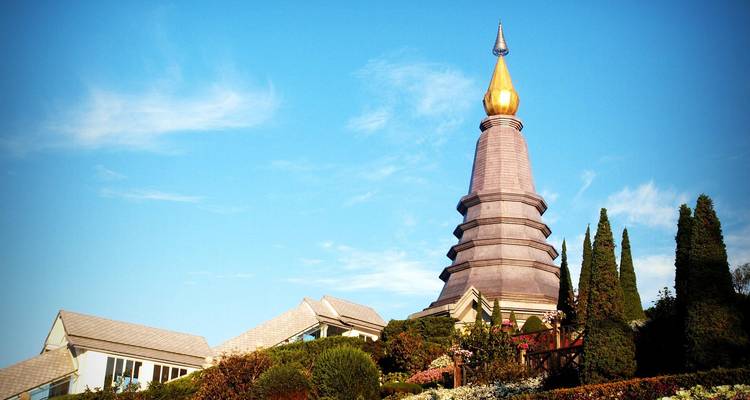 A large pagoda with manicured gardens under a blue sky.