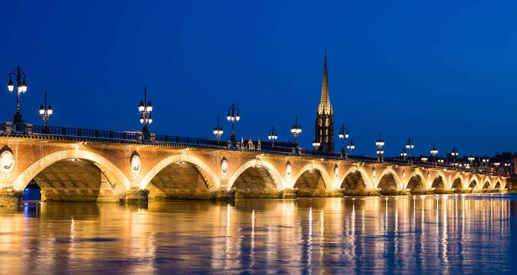 El puente Pont de Pierre en Burdeos iluminado por la noche.