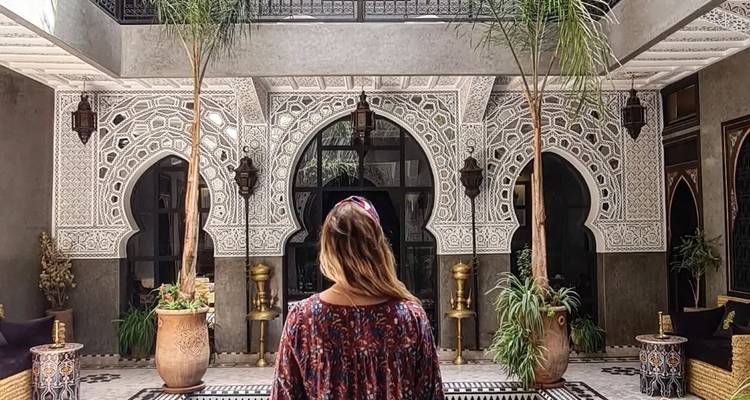 Person, die in einem wunderschön dekorierten traditionellen marokkanischen Innenhof steht.