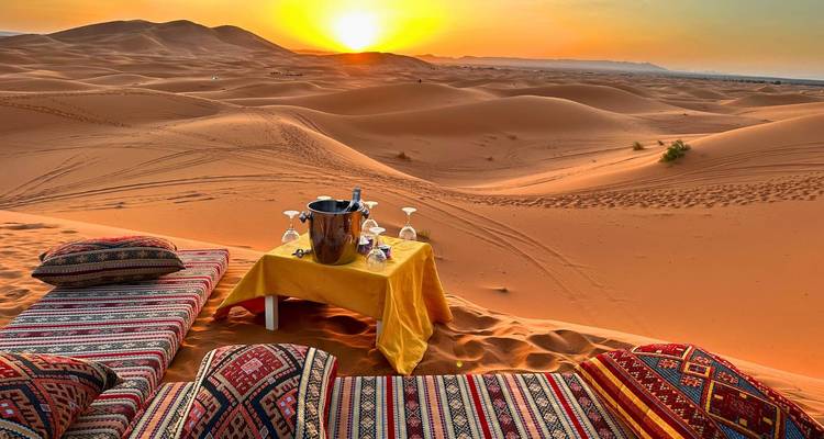 Un aménagement accueillant avec des coussins moelleux et une petite table sur les dunes au coucher du soleil.