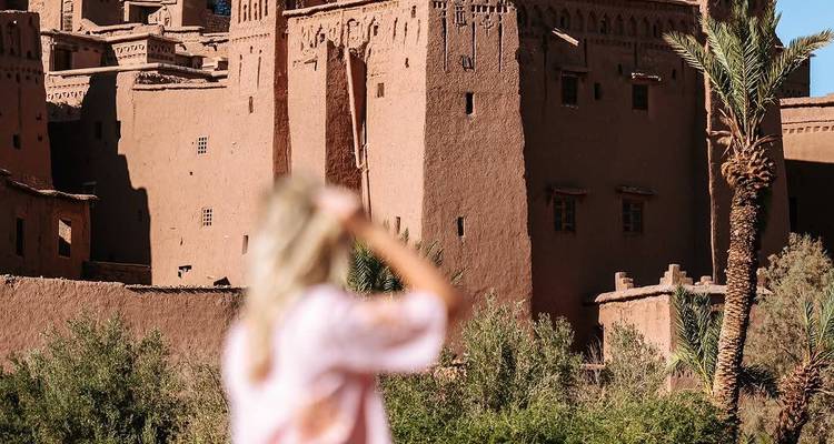 Une personne regardant une structure traditionnelle en briques de terre crue.