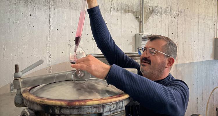 Homme dégustant du vin d'un grand fût dans une cave à vin.