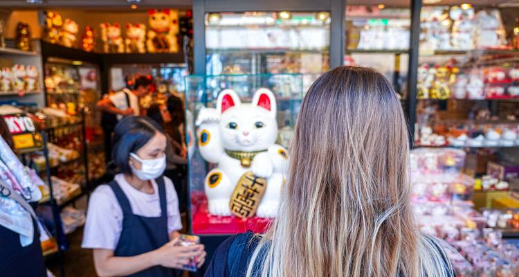 Frau beobachtet eine große Maneki-neko in einem Geschäft.