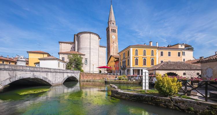 Des bâtiments colorés avec un pont au-dessus d'un canal sous un ciel bleu.