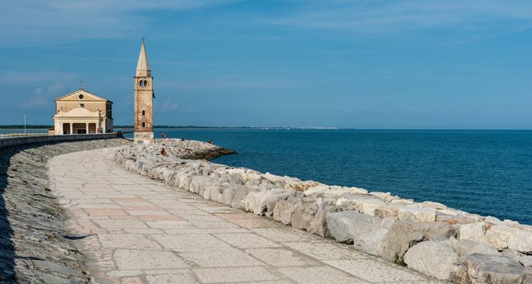 Église et clocher sur une promenade au bord de la mer.