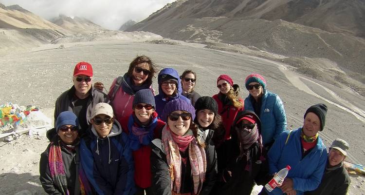 Groupe de personnes posant pour une photo dans un terrain montagneux accidenté.