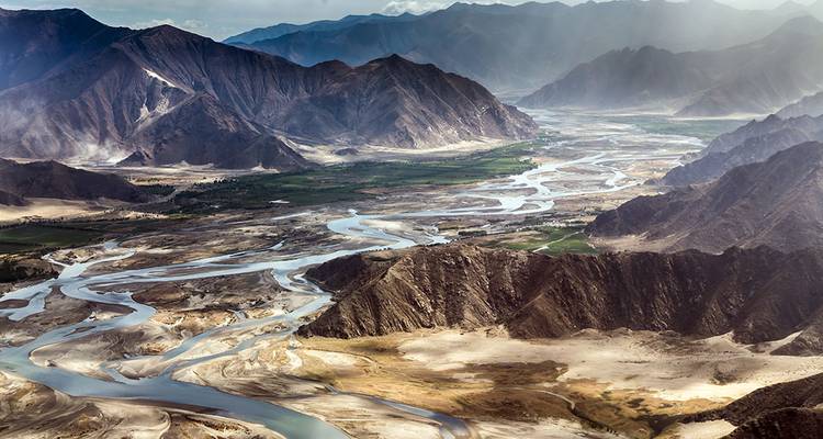 Vue panoramique d'une vallée fluviale avec des cours d'eau sinueux.