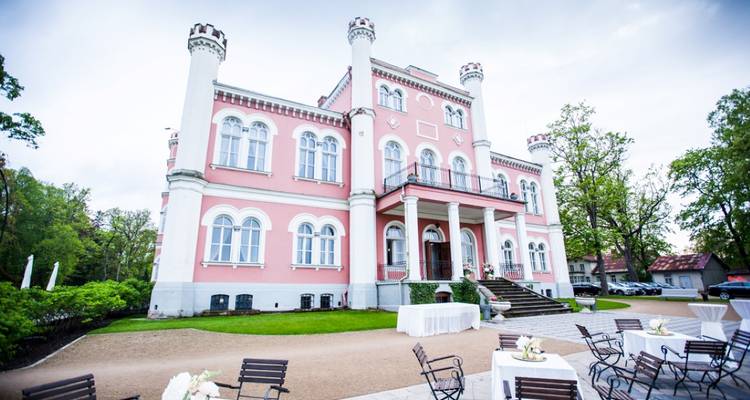 Een romantisch roze neo-gotisch herenhuis met torentjes is ingericht voor een buitenevenement.