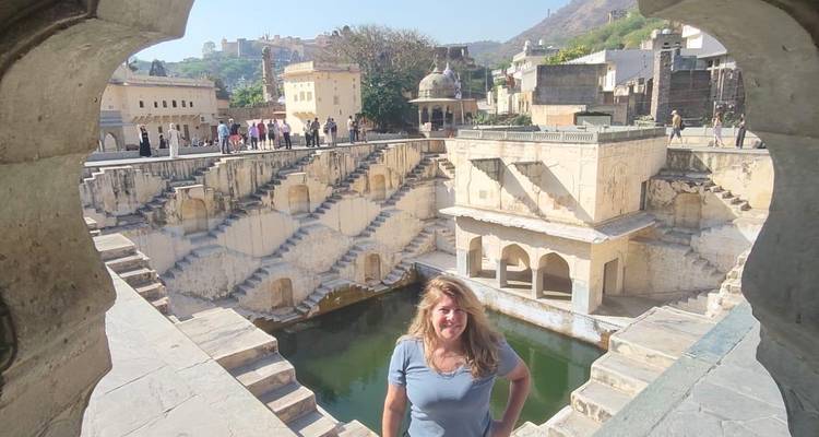 Une femme posant près d'un grand puits à degrés historique.