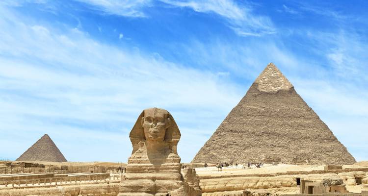 Vista icónica de la Gran Esfinge con las Pirámides de Giza bajo un cielo azul brillante.