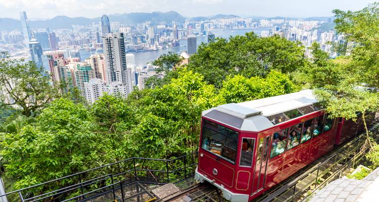 Historic tram ascending a hillside with a cityscape view.