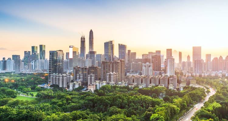 Skyline of a bustling city with lush greenery in the foreground.
