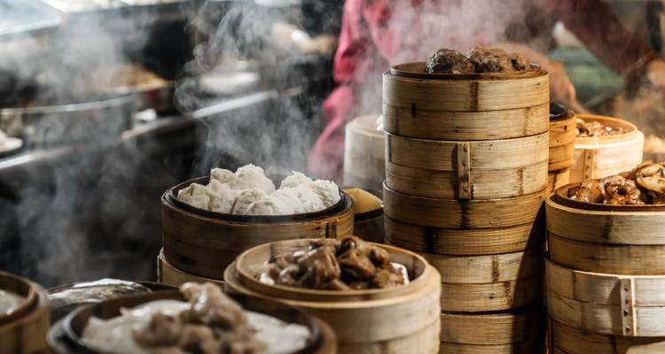 Stacks of steaming bamboo baskets containing various dim sum in a restaurant setting.