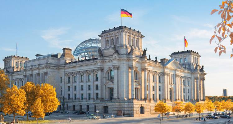 Un autre angle du bâtiment historique du parlement du Reichstag avec sa coupole de verre et son feuillage doré.