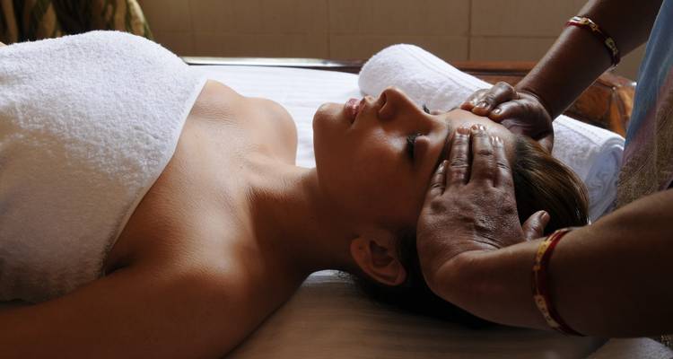 Eine Person, die eine Stirnmassage in einer Spa-Umgebung erhält.