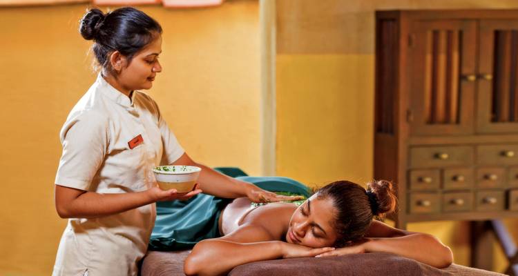 Eine Frau, die eine therapeutische Massage mit aufgetragenen Kräutern erhält.