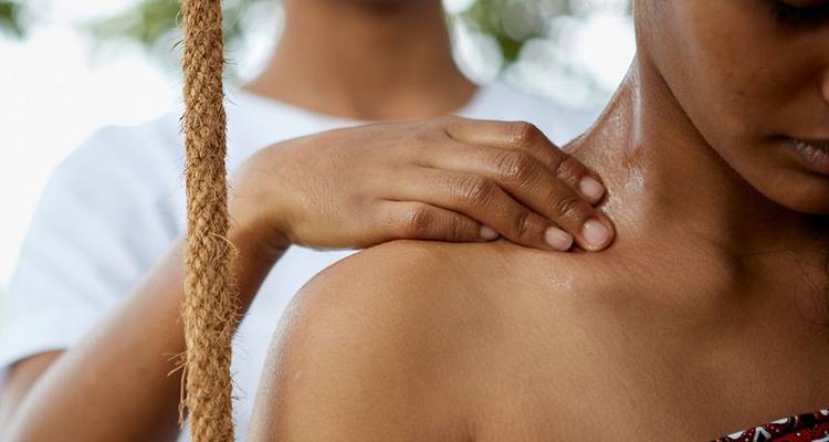 Eine Nahaufnahme von jemandem, der eine Schultermassage erhält, mit Blick ins Freie.