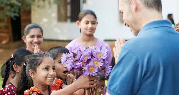 Eine Gruppe örtlicher Kinder, die einem Besucher Blumen anbietet.
