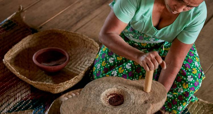 Eine Frau, die Gewürze mit einer traditionellen Steinmühle mahlt.
