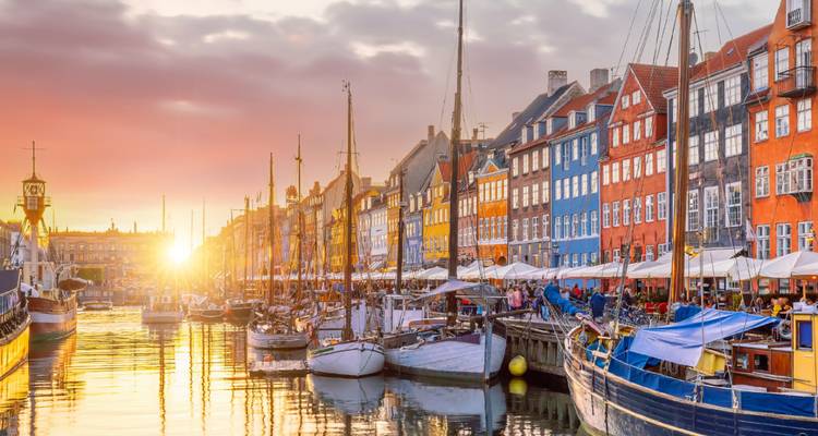 Sunset over a colorful canal with boats and buildings.