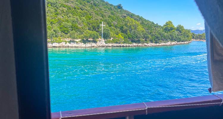 A coastal view from a boat window with clear blue waters.