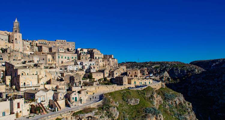 Panoramic view of a hillside ancient city under a bright blue sky.
