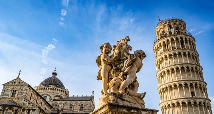 Der Schiefe Turm von Pisa und verzierte Domstatuen stehen vor einem klaren blauen Himmel.