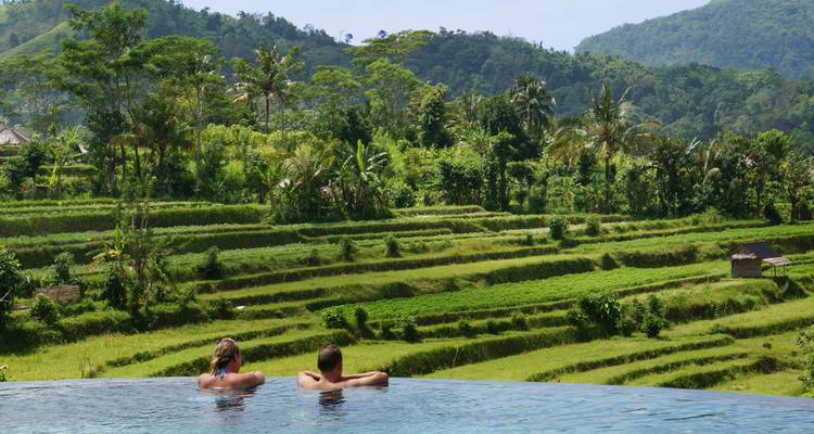 Zwei Menschen, die in einem Infinity-Pool schweben und auf Reisterrassen blicken