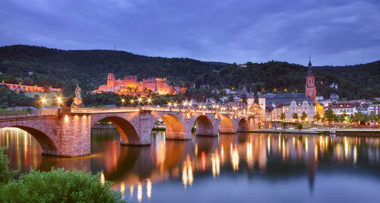 Pont historique au-dessus d'une rivière, magnifiquement éclairé la nuit.