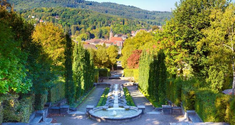 Jardins entretenus avec en arrière-plan des collines et des bâtiments.