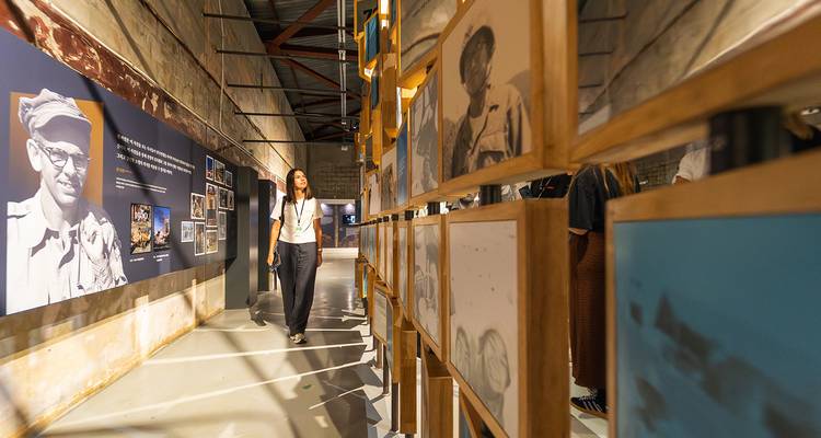 Une femme marchant à travers une exposition de musée avec des photographies et des textes.