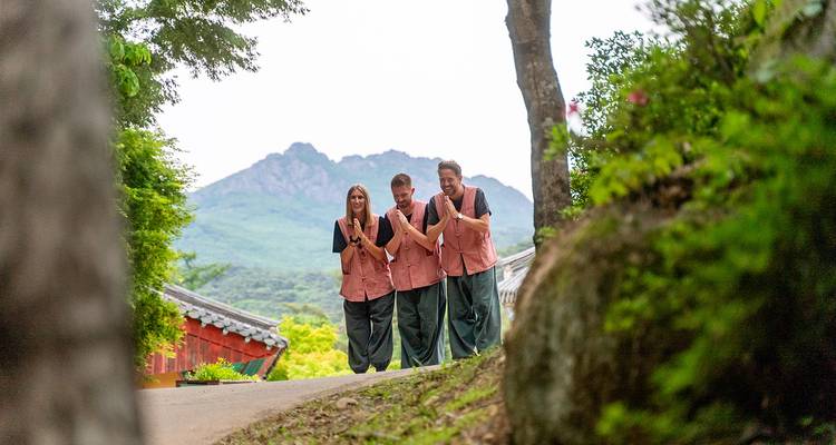 Trois personnes marchant sur un sentier avec des montagnes en arrière-plan.